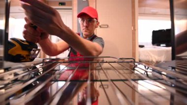 RV Industry Worker in His 40 'larında Travel Travel Trailer Sobası' nı modern karavanın içine yerleştiriyor. Endüstri Teması.