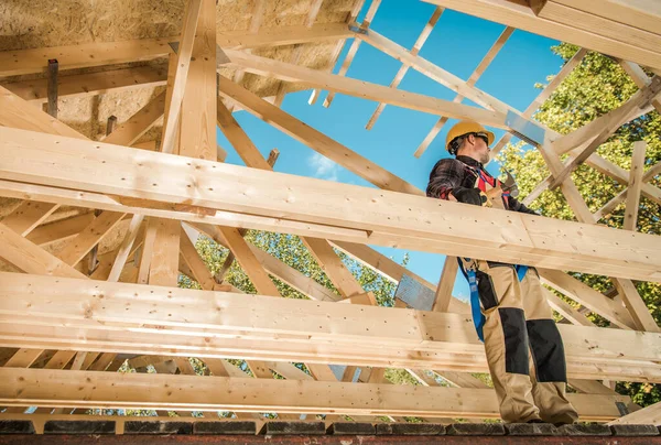 Skeleton Wood Frame Of House Building. Caucasian Contractor Worker on the Attic Frame. Industrial Theme.
