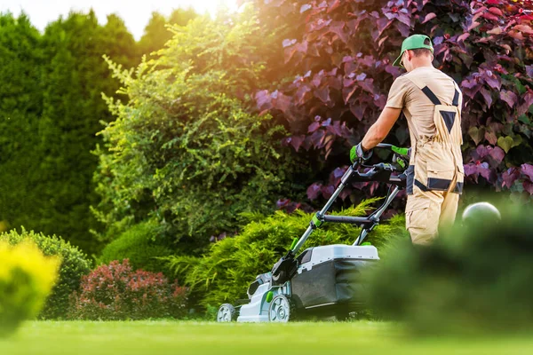 40代の白人住宅庭労働者は 電気コードレス草芝刈り機を使用して裏庭の芝生をトリミングします 園芸産業のテーマ — ストック写真