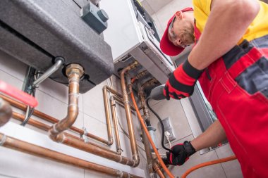 Professional Gas Heating Technician with Natural Gas Detector Device in His Hands Looking For Potential Leaks Inside the Heating Furnace System. clipart