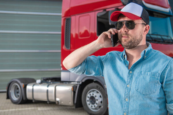 Caucasian Semi Truck Driver in His 30s Ordering New Tractor Truck Parts by Phone Next. Heavy Duty Transportation Industry.