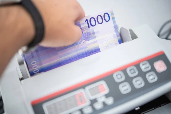 Caucasian Bank Worker and Norwegian Krone Bills Counting Using Money Counter. Financial Theme.