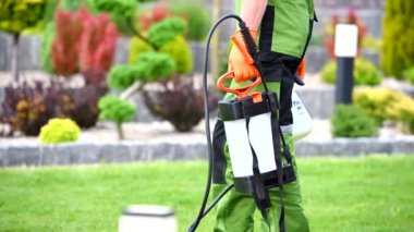 Kırklı yaşlarındaki beyaz işçi haşere ilaçlama ekipmanlarını hazırlıyor. Spring Garden Bakım TemasıName.