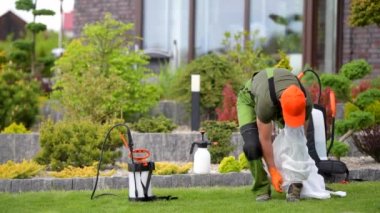 Kırklı yaşlarındaki beyaz işçi haşere ilaçlama ekipmanlarını hazırlıyor. Spring Garden Bakım TemasıName.