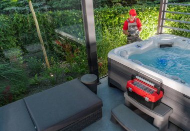 40 'lı yaşlarındaki Spa Teknisyeni Garden SPA Gazebos' un içine yerleştirildikten hemen sonra jakuzi kontrolü yapıyor. Modern Mimari Jakuzi Barınağı