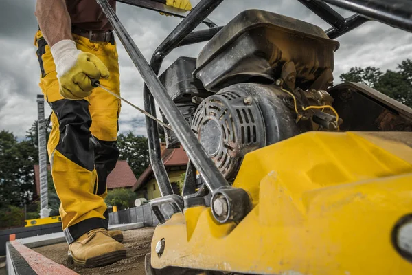 40代でプロの白人建設労働者によって運営されている土壌コンパクタ レンガ舗装用土の準備 — ストック写真