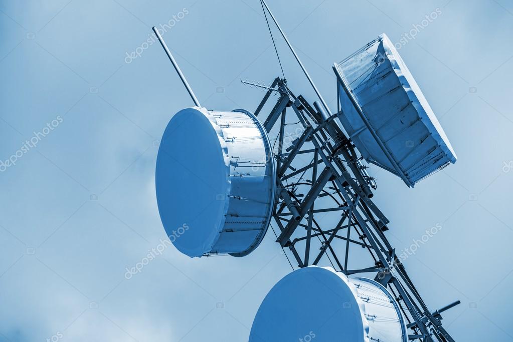 Closeup Of Microwave Dish On High Antenna Tower And Blue Sky