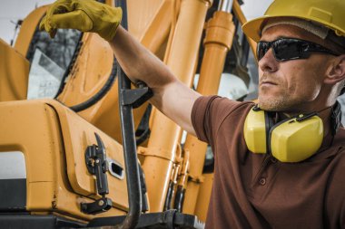 İnşaat işçisi, inşaat sahasında çalışırken güvenlik gözlüğü takıyor ve makineleri çalıştırıyor..