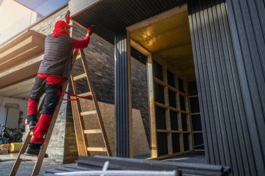 Bir işçi gün içinde binanın dışını onarmak için bir merdivenin üzerinde durur. Bölge inşaatla meşgul..