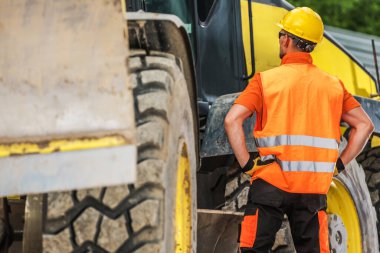 Bir inşaat işçisi gündüz saatlerinde iş yerinde ağır ekipmanlara bakar..