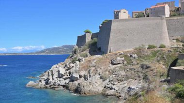 Calvi kalesi mavi denize bakan kayalık bir sahilde duruyor. Korsika, Fransa