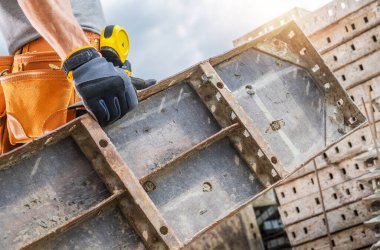 İnşaat işçisi gün içinde inşaat alanında çalışırken beton bir form tutar..