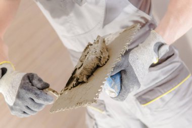 Bir kişi inşaat alanında çimento uygulamak için malayla çalışır..