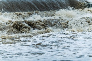 Okyanusun fırtınalı bir gününde kıyıya güçlü dalgalar, su ve köpük sıçratır..