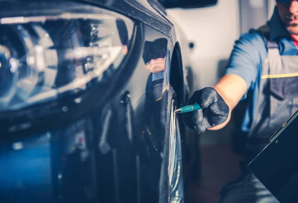 Bir teknisyen atölyede bir araba üzerinde çalışıyor, lastiği ya da tekerleği kontrol ediyor..