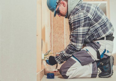 Bir işçi inşaat sırasında elektrik prizine kablo bağlar..