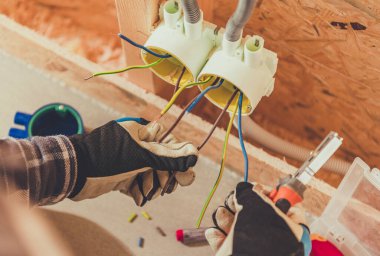 Bir insan kabloları birbirine bağlar ve onları bir sitede elektrik kutularına bağlar..