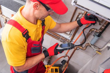 Tesisatçı evdeki sızıntıları kontrol etmek için bir aletle borular üzerinde çalışır..