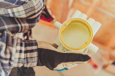 Bir kişi dairesel sarı bir elektrik kutusu bileşeni tutuyor.