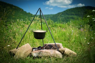 Ateşin üzerinde asılı duran bir turist potası.