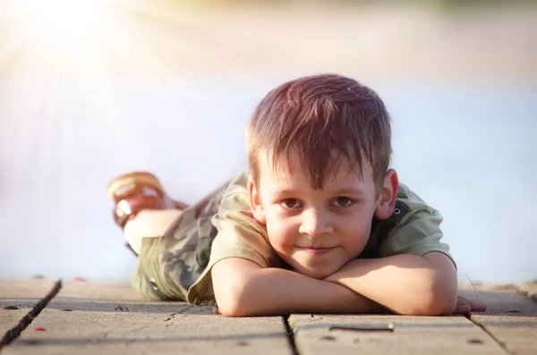 Junge liegt auf Holzplattform — Stockfoto