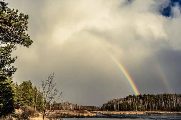 Rainbow in the spring sky on the background of the lake