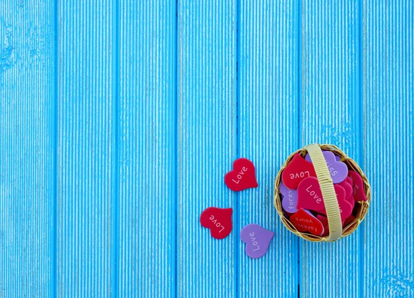 Fond d'amour. Panier complet avec des cœurs sur un fond en bois bleu — Photo