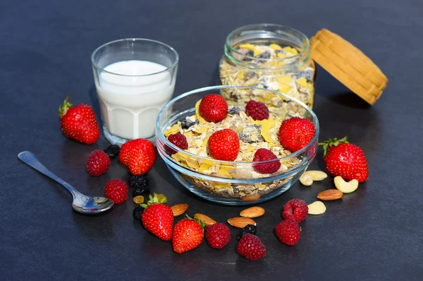 Müsli mit Milch, Nüssen und Beeren zum Frühstück auf dunklem Hintergrund — Stockfoto