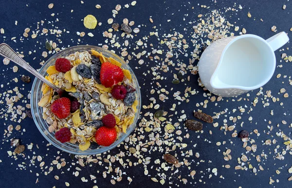 Müsli mit Milch, Nüssen und Beeren zum Frühstück auf dunklem Hintergrund — Stockfoto