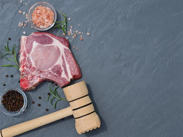 Carne fresca cruda e martello sul piano del tavolo in pietra naturale — Foto Stock