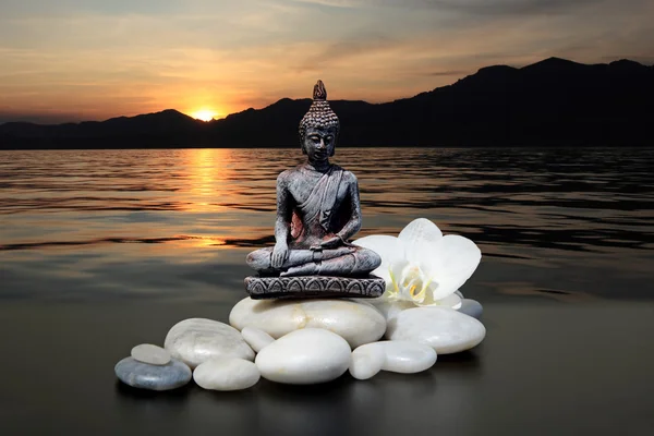 Zen veya Feng-Shui arka plan-Buddha, zen stone, beyaz orkide çiçekler. Arka planda, güneşin dağların arkasında ayarlar. — Stok fotoğraf