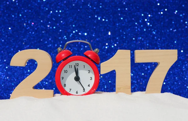Feliz año nuevo 2017 tarjeta de felicitación. Reloj despertador y los números 2017 en una deriva de nieve sobre un fondo de brillo azul — Foto de Stock