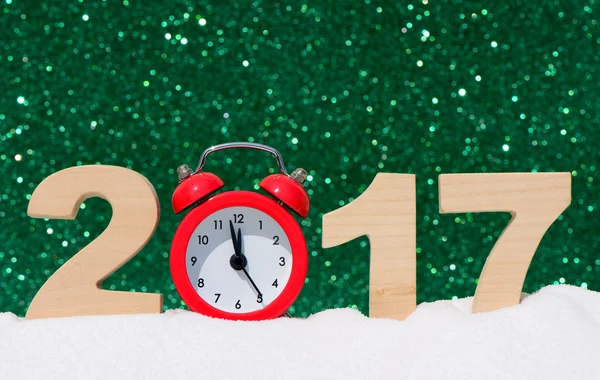Feliz año nuevo 2017 tarjeta de felicitación. Reloj despertador y los números 2017 en una deriva de nieve sobre un fondo de brillo — Foto de Stock