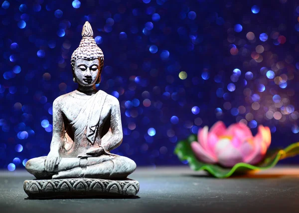 Estatua de Buda Zen y una flor de loto sobre un brillante fondo de brillo brillante con bokeh —  Fotos de Stock