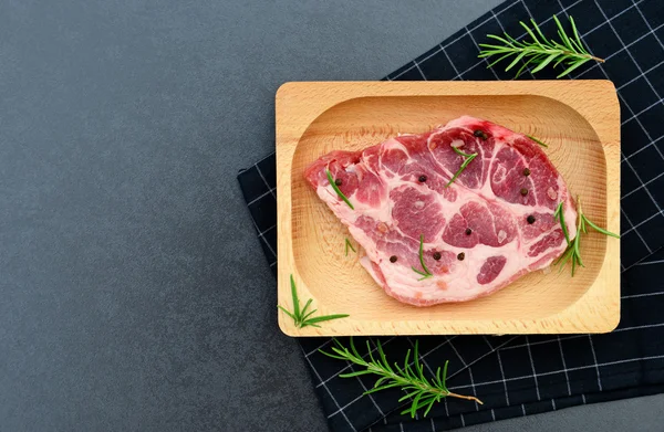 Carne di maiale cruda e rosmarino su fondo di granito nero — Foto Stock