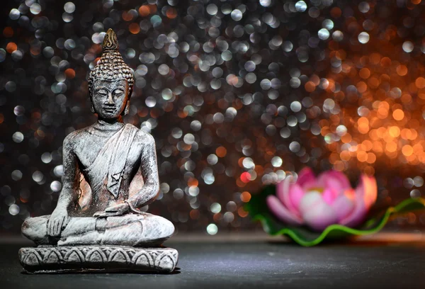 Estatua de Buda Zen y una flor de loto sobre un brillante fondo de brillo brillante con bokeh —  Fotos de Stock