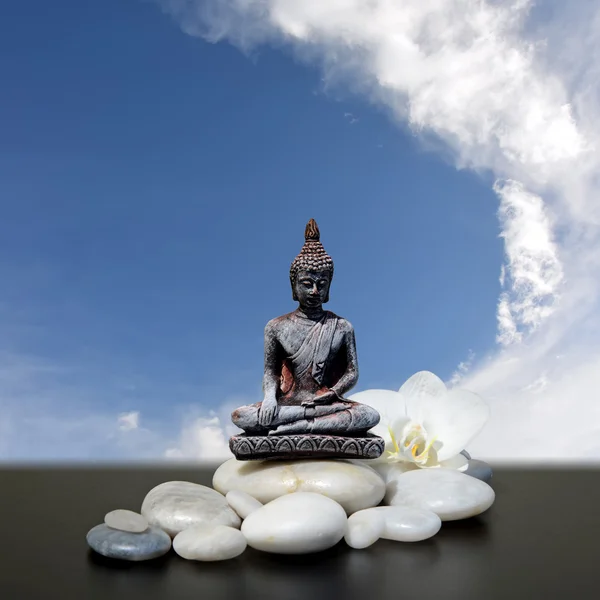 Buddha, piedra zen, flores blancas de la orquídea y fondo del cielo —  Fotos de Stock