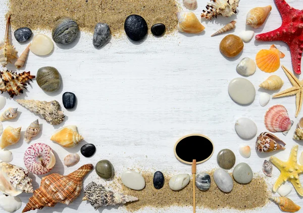 Conchas do mar, estrelas do mar, seixos e placa preta vazia para texto sobre um fundo de madeira branco — Fotografia de Stock