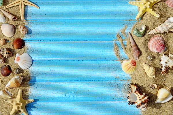 Kum, deniz kabuklarını ve denizyıldızı mavi ahşap arka plan üzerinde — Stok fotoğraf
