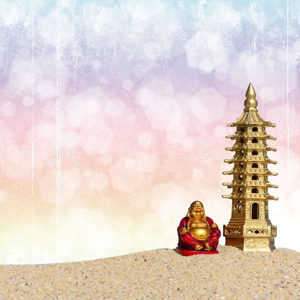 Laughing Buddha and seven-storied pagoda in the sand. Symbol of good luck and prosperity in Feng-Shui