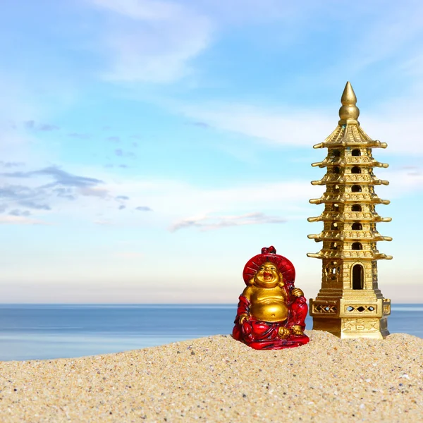 Смеющийся Будда и семиэтажная пагода в песке. Символ удачи и процветания в Фэн-Шуй — стоковое фото