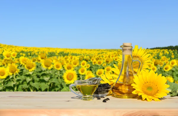 Sonnenblumen, Samen und Sonnenblumenöl. Im Hintergrund ein Sonnenblumenfeld — Stockfoto