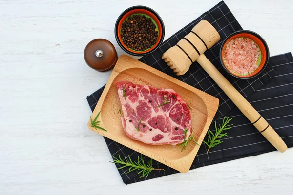 Rohes Fleisch auf Holzteller, Rosmarin, Gewürze und Hammer auf schwarz-weißem Hintergrund — Stockfoto