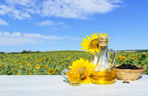 Sonnenblumen, Samen und Sonnenblumenöl. Im Hintergrund ein Sonnenblumenfeld — Stockfoto