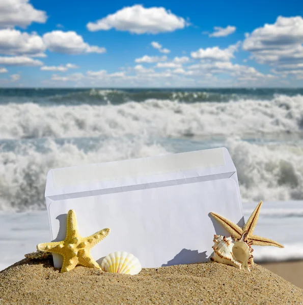 Seashells and starfish with open envelope with blank letter on sand beach — Stock Photo, Image