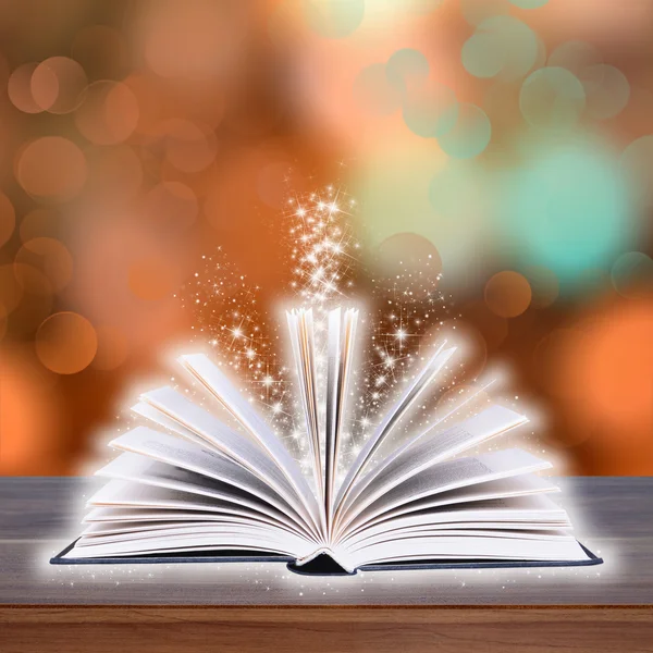 Libro aperto con bokeh luce su tavole di legno e sfondo scuro astratto — Foto Stock