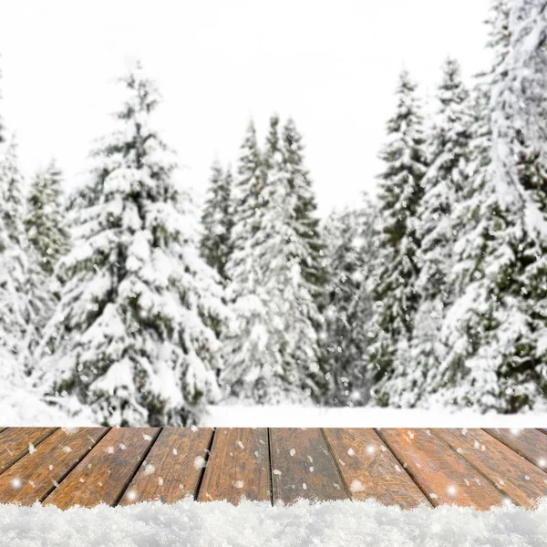 Blurred winter background with snow covered forest and shabby table — 图库照片