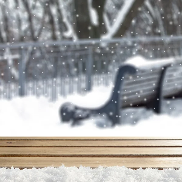 Blurred winter background with snow covered forest and shabby table — Stock fotografie