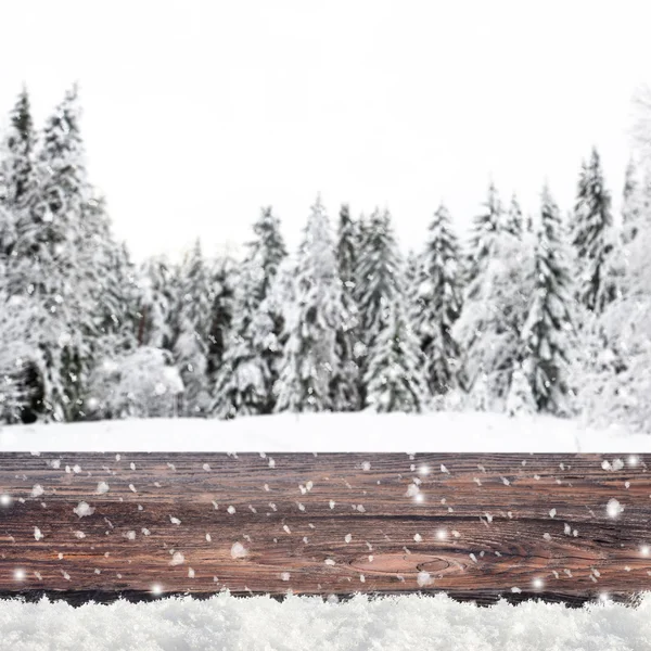 Blurred winter background with snow covered forest and shabby table — Zdjęcie stockowe