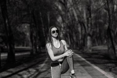 Spor kıyafetleri ve gözlükleriyle parkta güzel bir atletik kız. Sağlıklı bir yaşam tarzı. Yumuşak seçici odak.